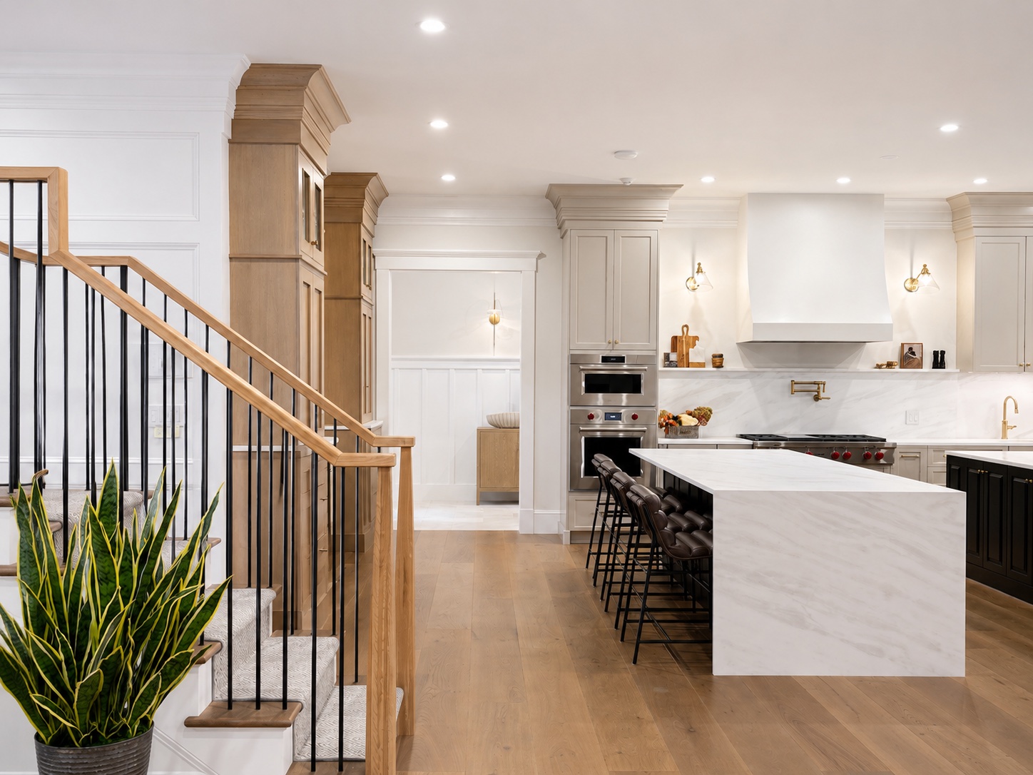 Kitchen cabinet finishing with taupe perimeter cabinets, black island, white counters, and brass hardware