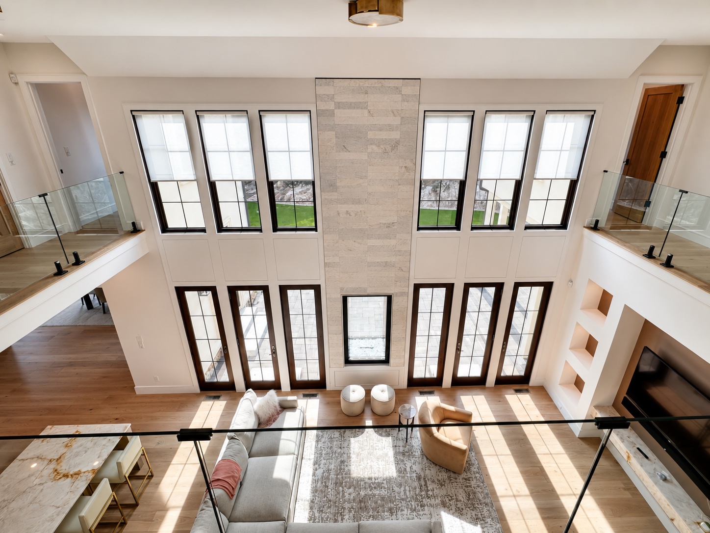 White foyer painting with coffered ceiling, black railings, marble floors, and large glass doors